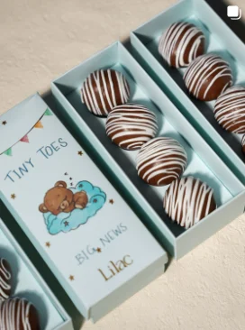 Lilac Mithai Studio Instagram post: "Tiny Toes" baby announcement boxes with chocolate-striped sweets